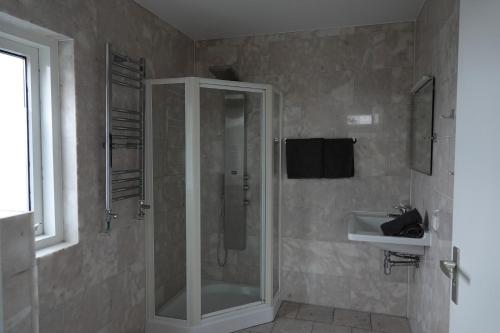 ein Badezimmer mit Dusche und Waschbecken in der Unterkunft Huize de Duinen in Bergen aan Zee