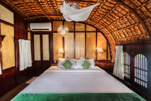 a bedroom with a large bed with a wooden ceiling at Spice Coast Cruises - Houseboat, A CGH Earth Experience in Alleppey