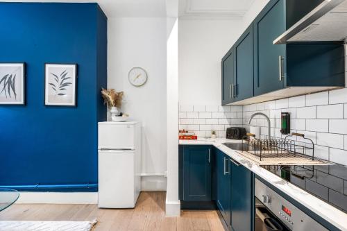 a kitchen with blue cabinets and a white refrigerator at Modern and spacious maisonette in Brighton & Hove