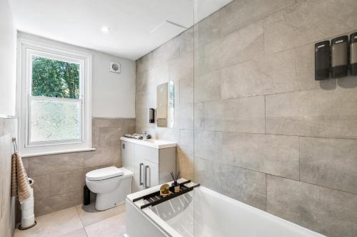 a bathroom with a tub and a toilet and a window at Modern and spacious maisonette in Brighton & Hove