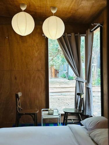 a bedroom with a bed and two chairs and a window at Cabin Home อยู่ป่า wild and free in Ko Larn