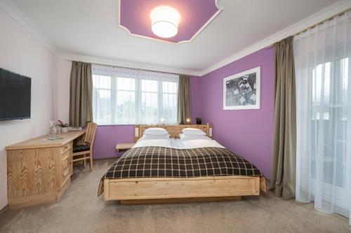 a bedroom with purple walls and a bed and a desk at Hotel Garni Carl Michael in Strobl
