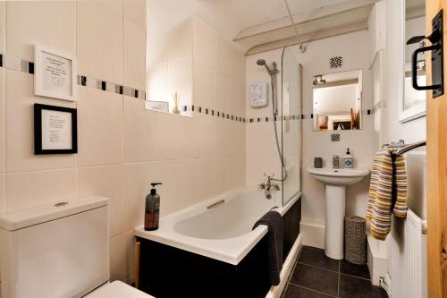 a bathroom with a sink and a tub and a toilet at Finest Retreats - Wallis Cottage in Fishguard