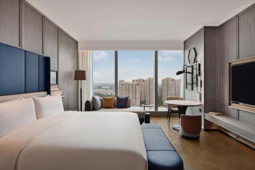 a hotel room with a large bed and a tv at Le Meridien Nantong in Nantong