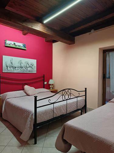 a bedroom with two beds and a pink wall at La casetta di nonna Sesa in Viterbo