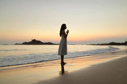 a woman in a white dress standing on the beach at SwaSwara Wellness - A CGH Earth Experience, Gokarna in Gokarna