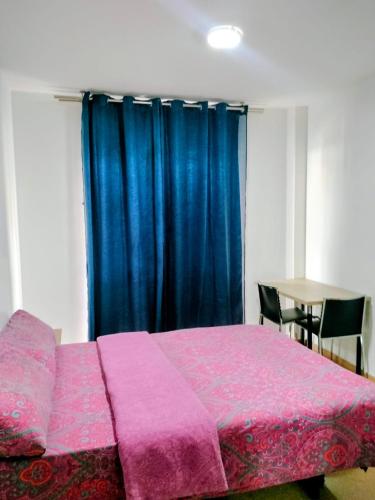 a bedroom with a pink bed with a blue curtain at EMMI Guesthouse in Alicante