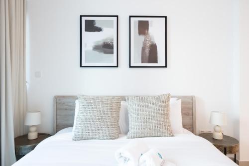 a bedroom with a white bed with three pictures on the wall at Bloomfields Dazzling 1BR in Saadiyat Island in Abu Dhabi