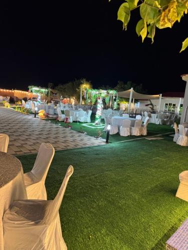 a group of tables and chairs on a lawn at night at Private farm Pool games Ras alkhaimah in Maghribīyah