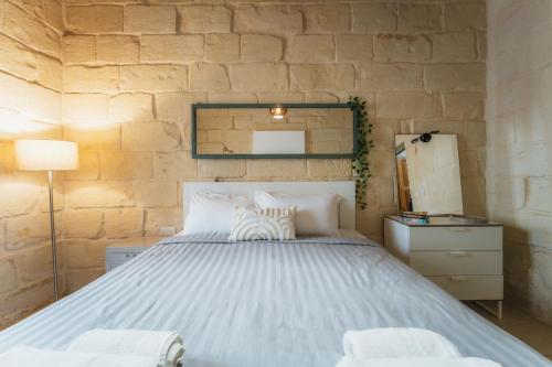 a bedroom with a large bed and a stone wall at Suite 3 at Palazzo Seraphim Boutique living in St Julians in St. Julianʼs