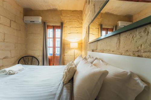 a bedroom with a bed with white sheets and pillows at Suite 3 at Palazzo Seraphim Boutique living in St Julians in St. Julianʼs