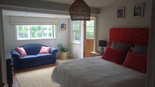 a bedroom with a bed and a blue couch and windows at Riverfront Guesthouse ,Watermeadows farm in Sedgefield