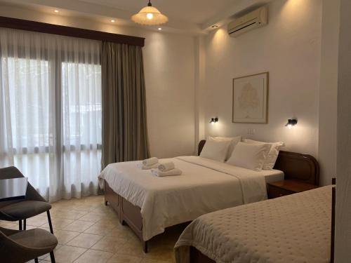 a hotel room with two beds and a window at Ξενώνας Ρόδον in Kato Loutraki