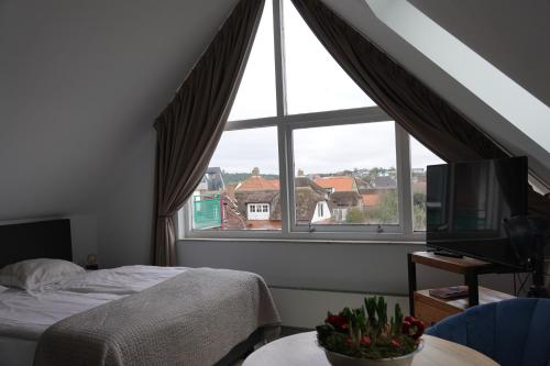 ein Schlafzimmer mit einem Bett und einem großen Fenster in der Unterkunft Huize de Duinen in Bergen aan Zee