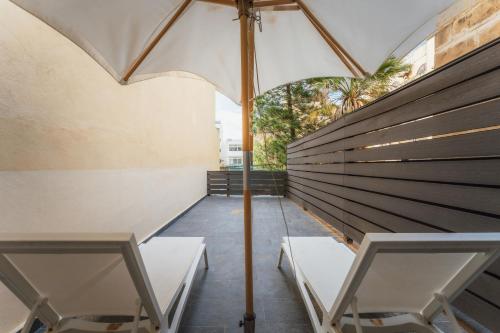 two white chairs and an umbrella on a patio at Suite 4 at Palazzo Seraphim Boutique living in St Julians in St. Julianʼs