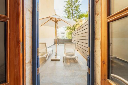 a patio with two chairs and an umbrella at Suite 4 at Palazzo Seraphim Boutique living in St Julians in St. Julianʼs