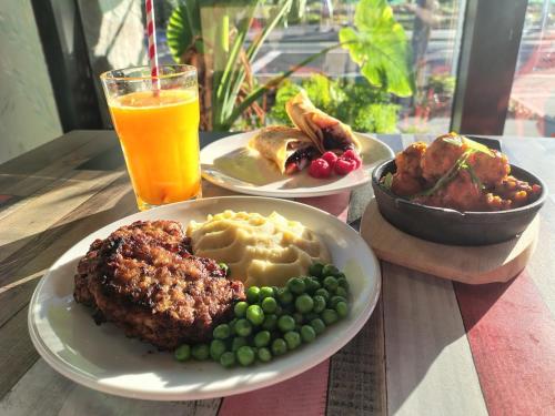 a table with two plates of food and a glass of orange juice at Breakfast & Dinner Included - Top-Floor Apartment Maroochydore CBD in Maroochydore