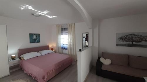 a bedroom with a pink bed and a couch at apartmani G&M in Bibinje