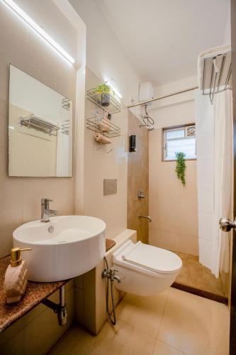 a white bathroom with a sink and a toilet at Charvi Reemz Anjuna in Anjuna
