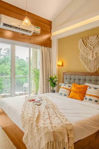 a bedroom with a large white bed and a window at Charvi Reemz Anjuna in Anjuna