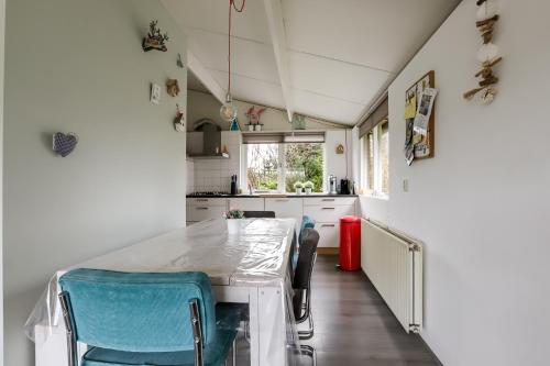 a kitchen with a white table and blue chairs at Rekerlanden 195 in Schoorldam
