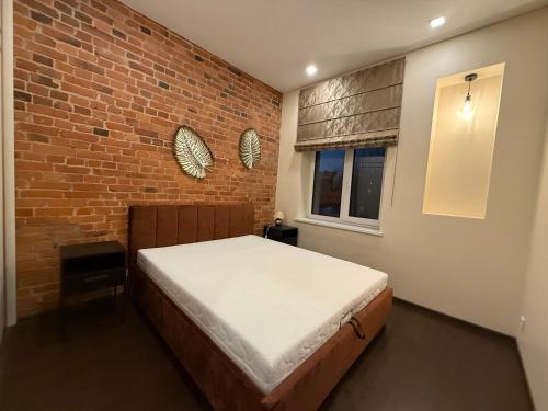 a bedroom with a bed and a brick wall at Kęstučio 66 apartamentai in Kaunas
