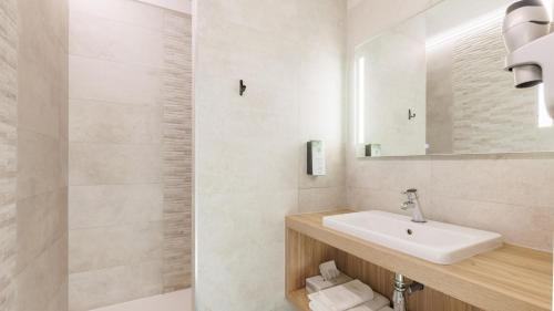 a white bathroom with a sink and a mirror at Kyriad Clermont Ferrand Nord - Riom in Riom