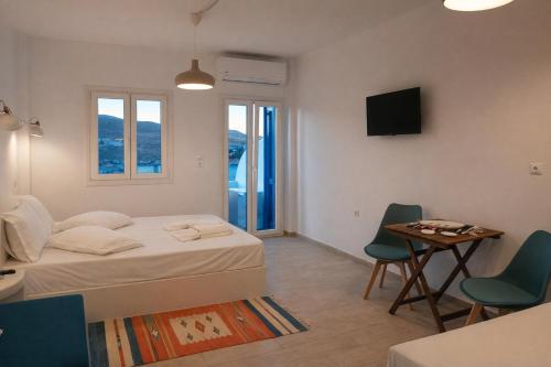 a bedroom with a bed and a table and chairs at Aiolos Studios Κythnos in Kithnos