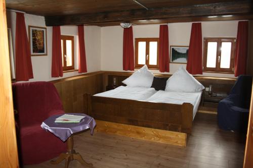 a bedroom with a bed and a chair and windows at Hotel Bärenhof in Philippsreut