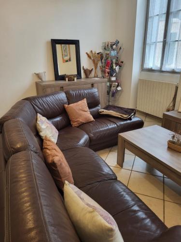 a brown leather couch in a living room with a table at entre arènes et maison carrée in Nîmes