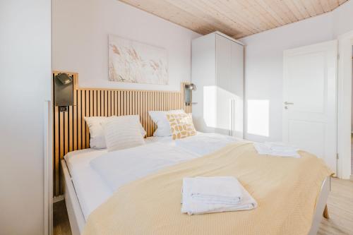 a white bedroom with a large bed with white sheets at Büdlfarm - Der Familien-Erlebnishof in Strandnähe in Fehmarn