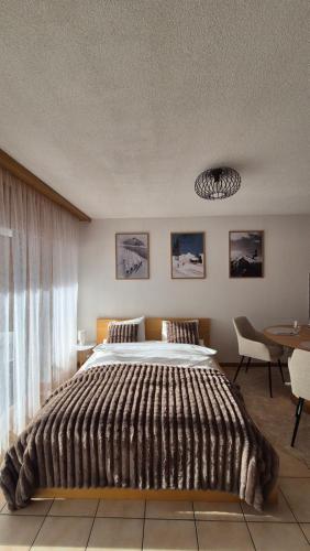 a bedroom with a large bed and a table at Summit & Spring Studio - Leukerbad in Leukerbad