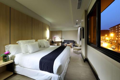 a hotel room with a large bed and a large window at Occidental Bilbao in Bilbao