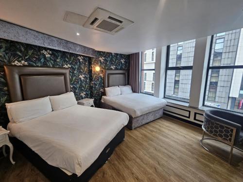 ein Hotelzimmer mit zwei Betten und Fenstern in der Unterkunft Print Works Hotel in Liverpool