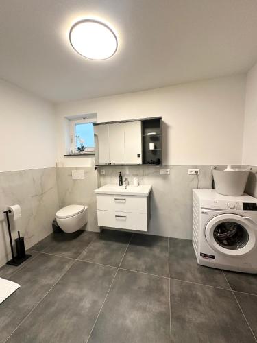 a bathroom with a toilet and a washing machine at Ferienwohnung am Wildpark Eichert HDH in Heidenheim an der Brenz