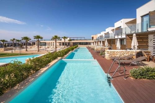 a pool at a resort with chairs and umbrellas at Barceló Nura in Sant Lluis
