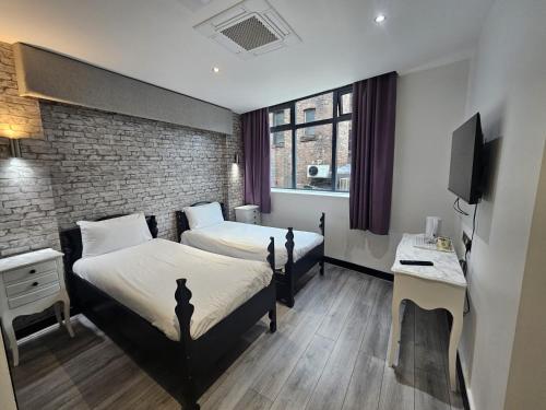 ein Hotelzimmer mit zwei Betten und einem Fernseher in der Unterkunft Print Works Hotel in Liverpool