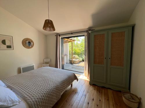 a bedroom with a bed and a sliding glass door at Les Iris - Maison chaleureuse in Montigné-sur-Moine