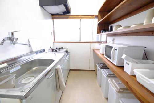 a kitchen with a sink and a microwave at JR松山駅から徒歩8分-最大6名-無料駐車場有り-松山一棟貸し宿Tsuji in Matsuyama