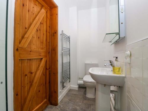 ein Badezimmer mit weißer Toilette und Holztür in der Unterkunft Castle Rag in Lydney