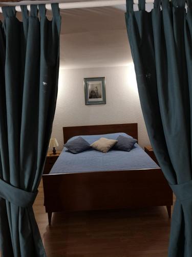 a bedroom with a bed with blue curtains at Maisonnette La Bienvenue in Trainel