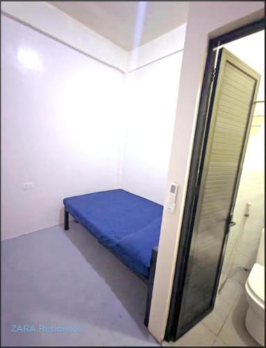 a small room with a blue bed in a bathroom at Zara Residence Room1 in Lagao