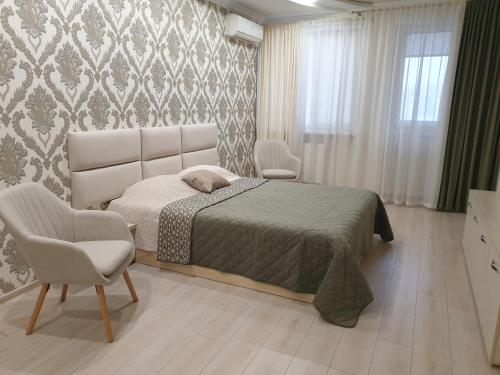 a bedroom with a bed and two chairs in it at Видові апартаменти на пляжі in Cherkasy