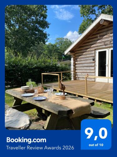 a wooden deck with a picnic table in front of a cabin at Knus boomstamhuisje op de Schatberg - nabij Toverland in Sevenum