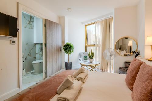 a bedroom with a large bed and a bathroom at Luxe London Retreat by Aureva Residences in London