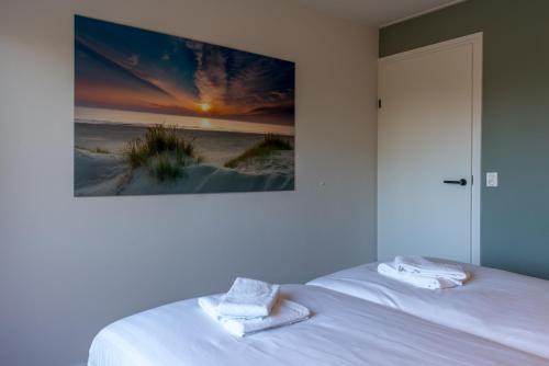 a bedroom with a bed with a painting on the wall at Zeebries in De Koog