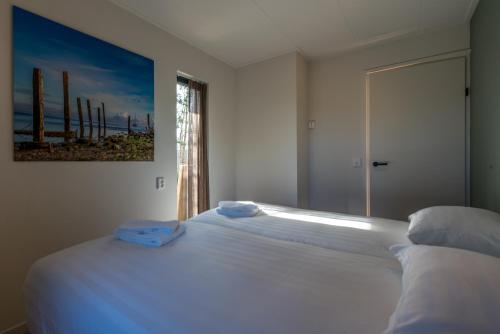 a bedroom with a white bed with towels on it at Zeebries in De Koog