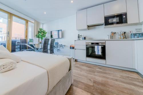 a white bedroom with a bed and a kitchen at Luxe London Retreat by Aureva Residences in London