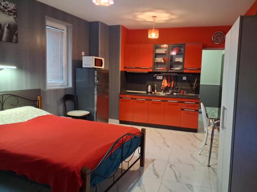 eine Küche mit roten Schränken und ein rotes Bett in einem Zimmer in der Unterkunft Studio Nera in Pomorie