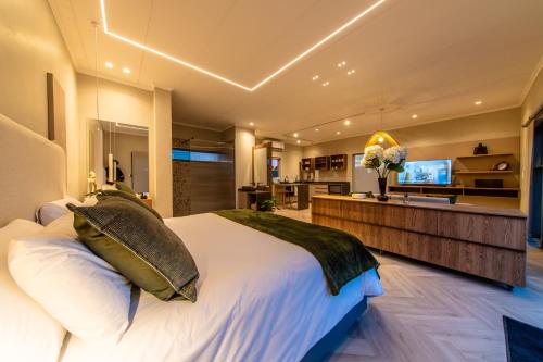 a bedroom with a large white bed and a kitchen at LEO Sky Farm Cottages in Simondium